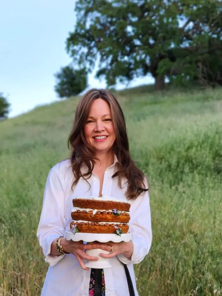 Amy holding a carrot cake in a meadow