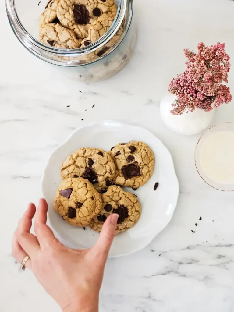 A plate of gluten free chocolate chip cookies and a glass of dairy free milk make for a delicious snack.