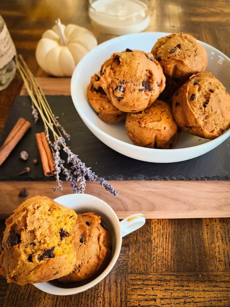 A bowl of pumpkin chocolate chip muffins and one muffin on a plate