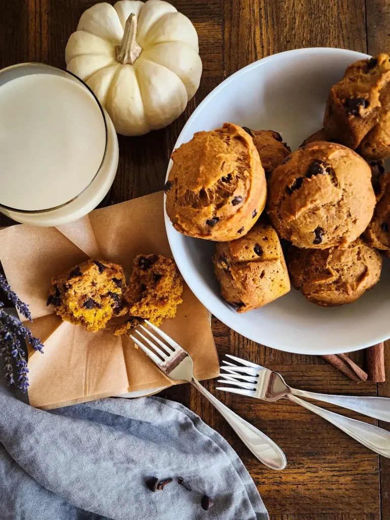 A bowl of gluten free pumpkin muffins and one muffin on a plate