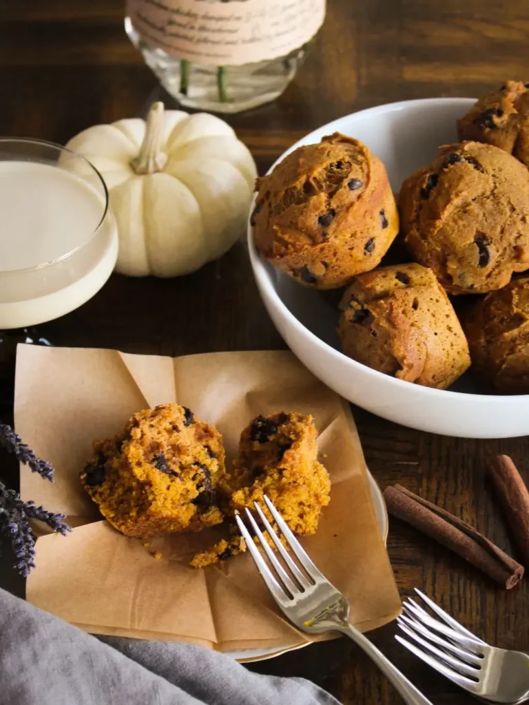 A bowl of pumpkin muffins and one muffin on a plate