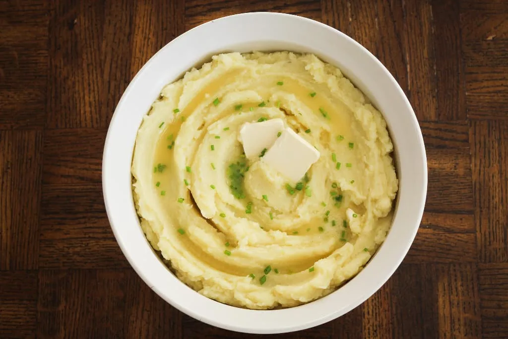 bowl of dairy free mashed potatoes with dairy free butter and chives on top