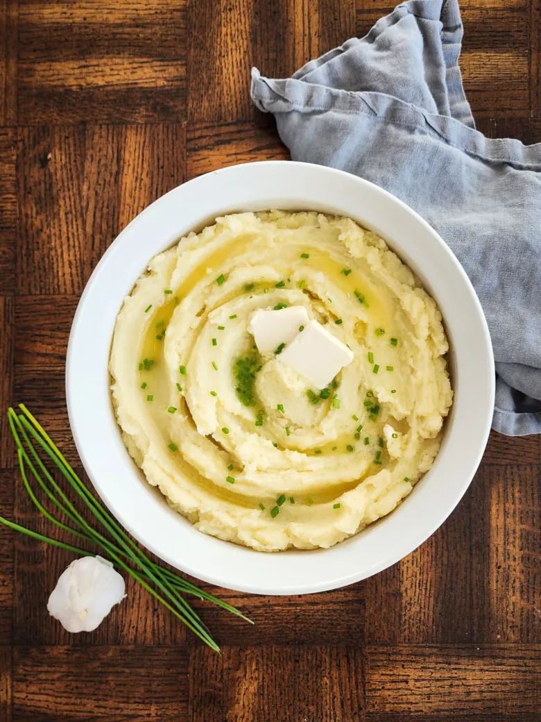 bowl of dairy free mashed potatoes with dairy free butter and chives on top