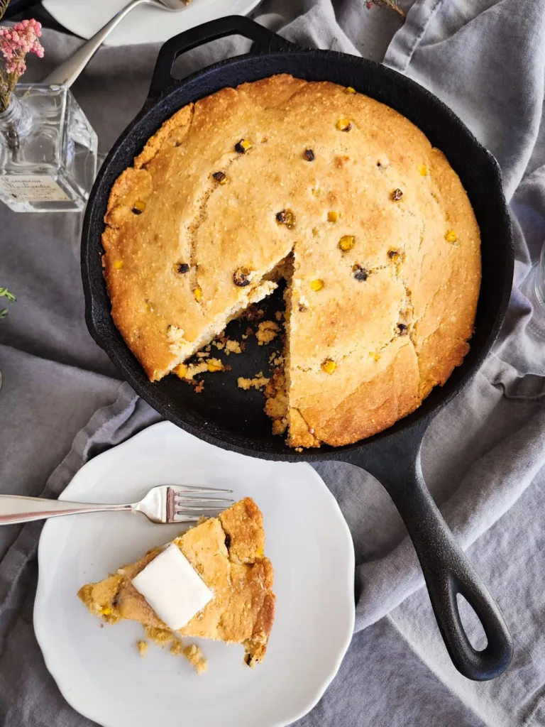 Gluten free cornbread in a cast iron skillet with a plate of cornbread