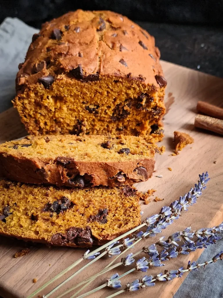 gluten free pumpkin bread that's been sliced, on a cutting board with lavender