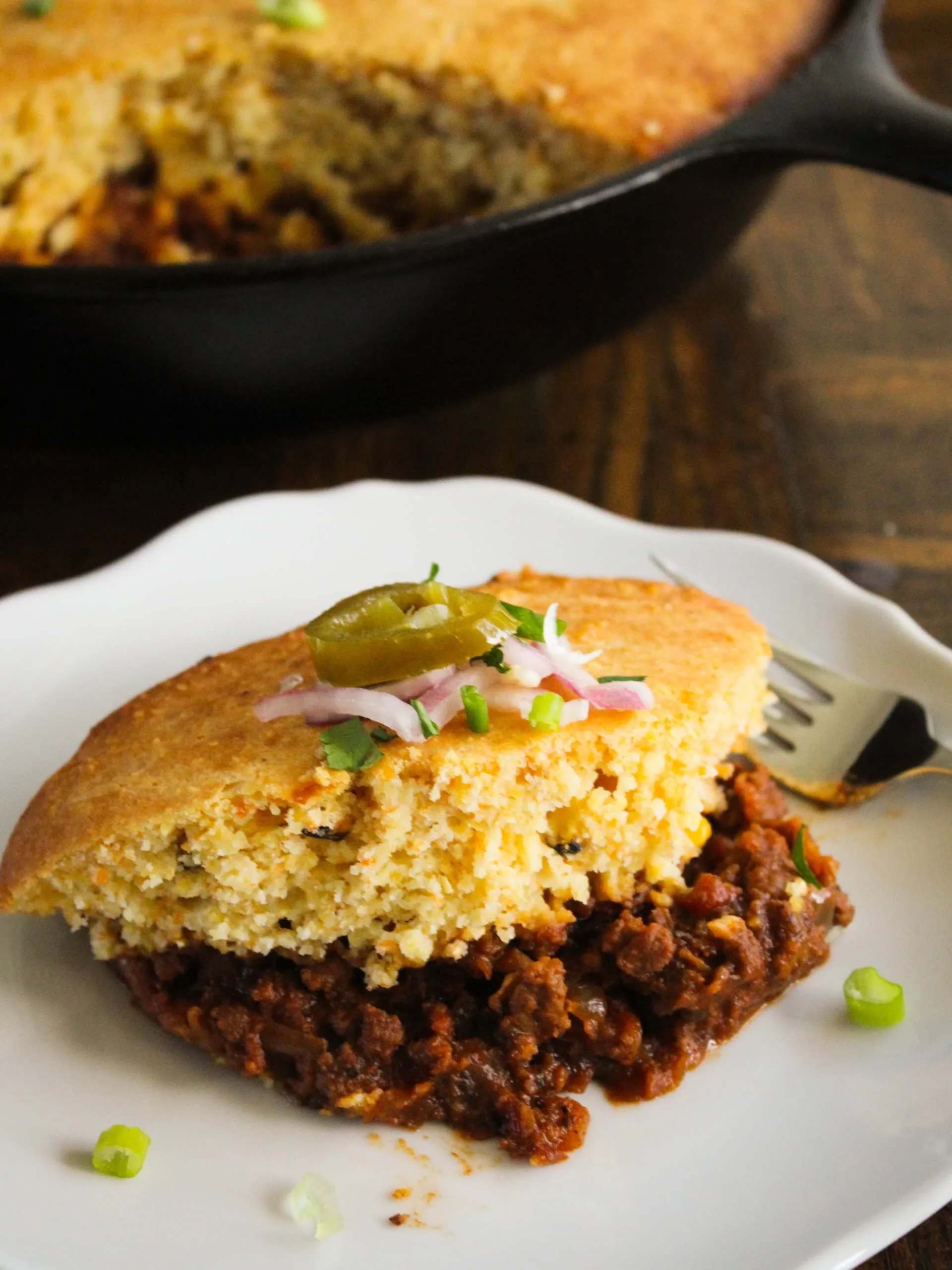 a piece of chili cornbread pie with all the fixins - rich, hearty, and delicious